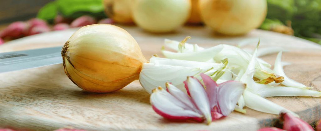 Closeup of various sliced onions on a cutting board